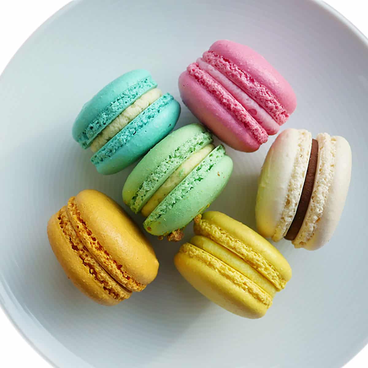 smooth round macarons in different colors on a plate.