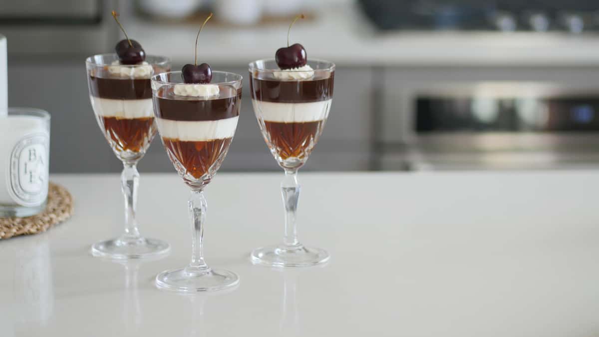 Three glass stems filled with coffee jelly, milk jelly and whipped cream.