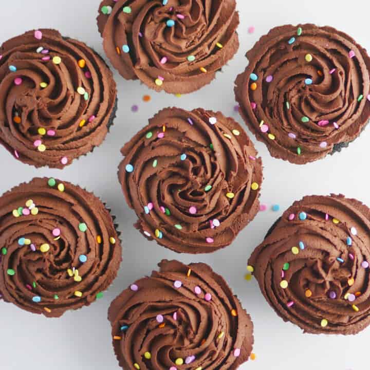 Cupcakes topped with chocolate whipped cream piped into swirls viewed from top down.