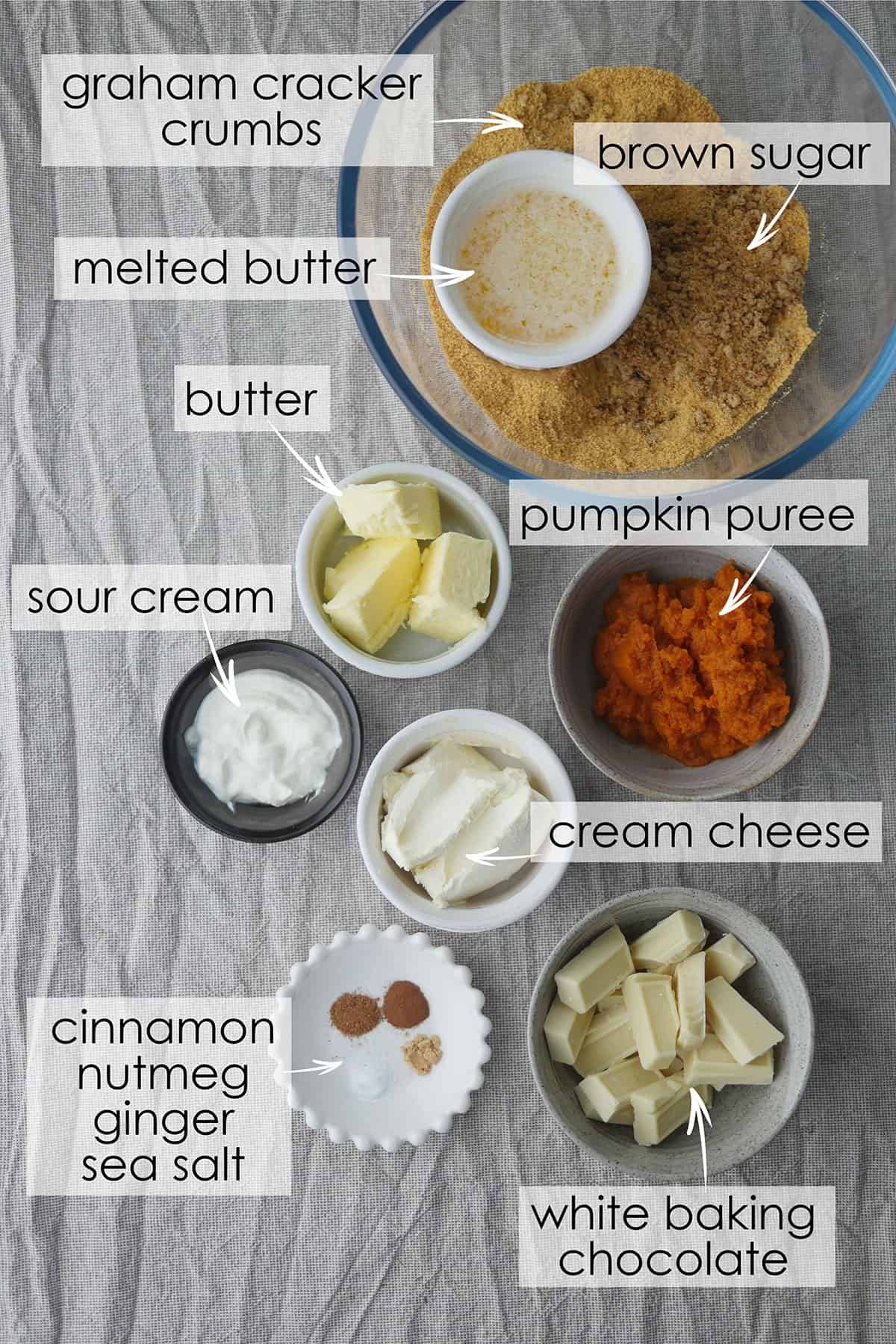 Ingredients for pumpkin cheesecake in individual ramekins laid on a table. 