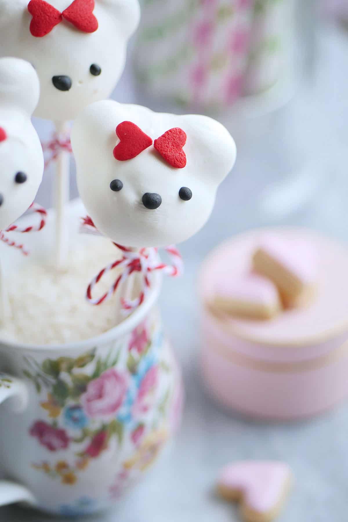Close up of bear donut hole lollipops with red heart sprinkle bows. 