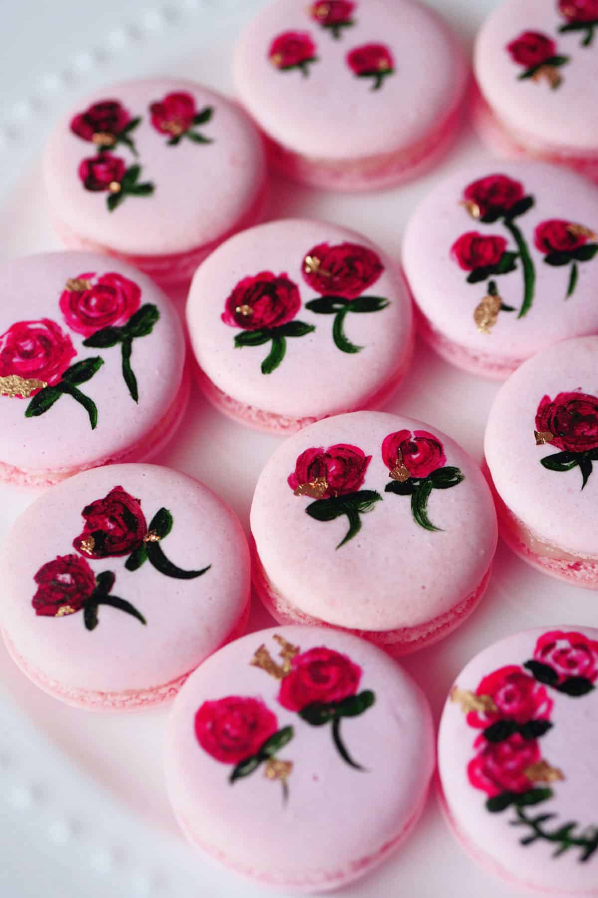 Close up of hand painted roses on macarons with gold flakes. 