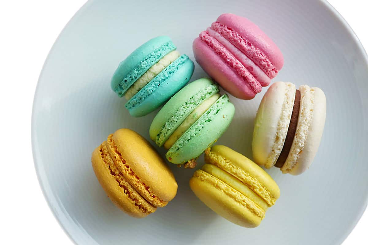 Round and smooth macarons in various colors on a grey plate.