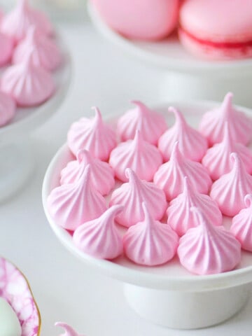 Pink meringue candy kisses on a small cupcake stand.