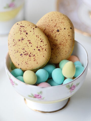 2 large speckled Easter egg macarons in a dish.