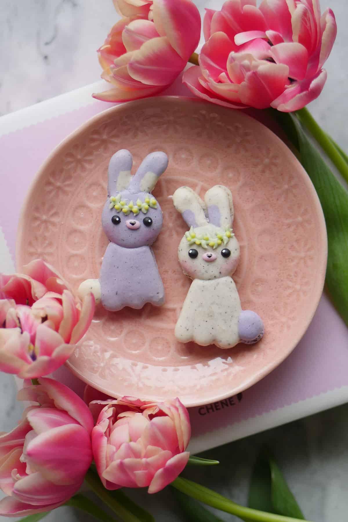 Naturally speckled lavender earl grey macarons in the shape of bunnies on a small plate. 