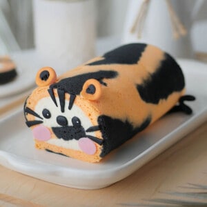 Tiger cake roll on a long plate placed on a table top.
