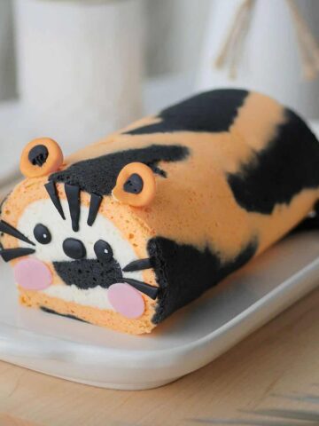 Tiger cake roll on a long plate placed on a table top.