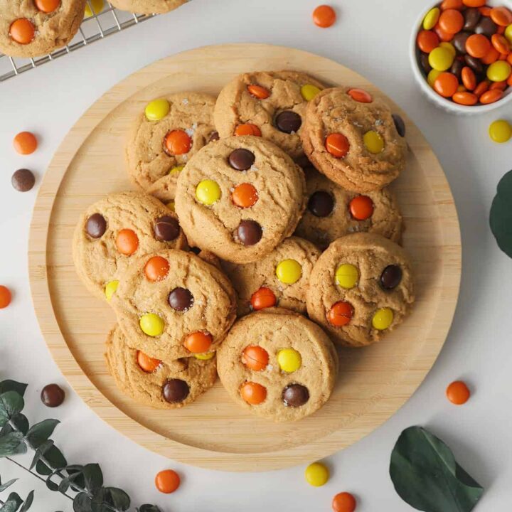 A wooden plate filled with Reese's candy peanut butter cookies.
