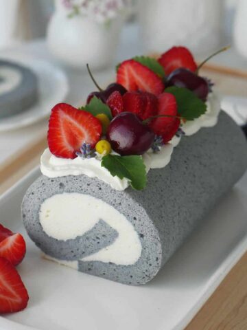 Earl Grey tea Swiss roll on a plate with strawberries on the side.