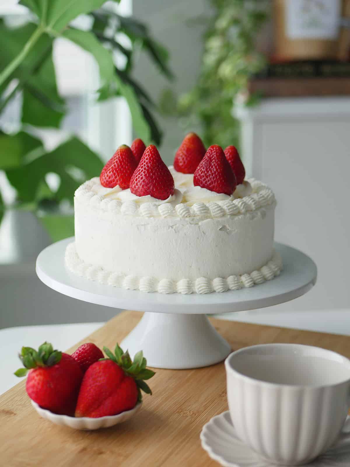 Full shot of the strawberry chiffon cake on a cake stand in the dining room. 