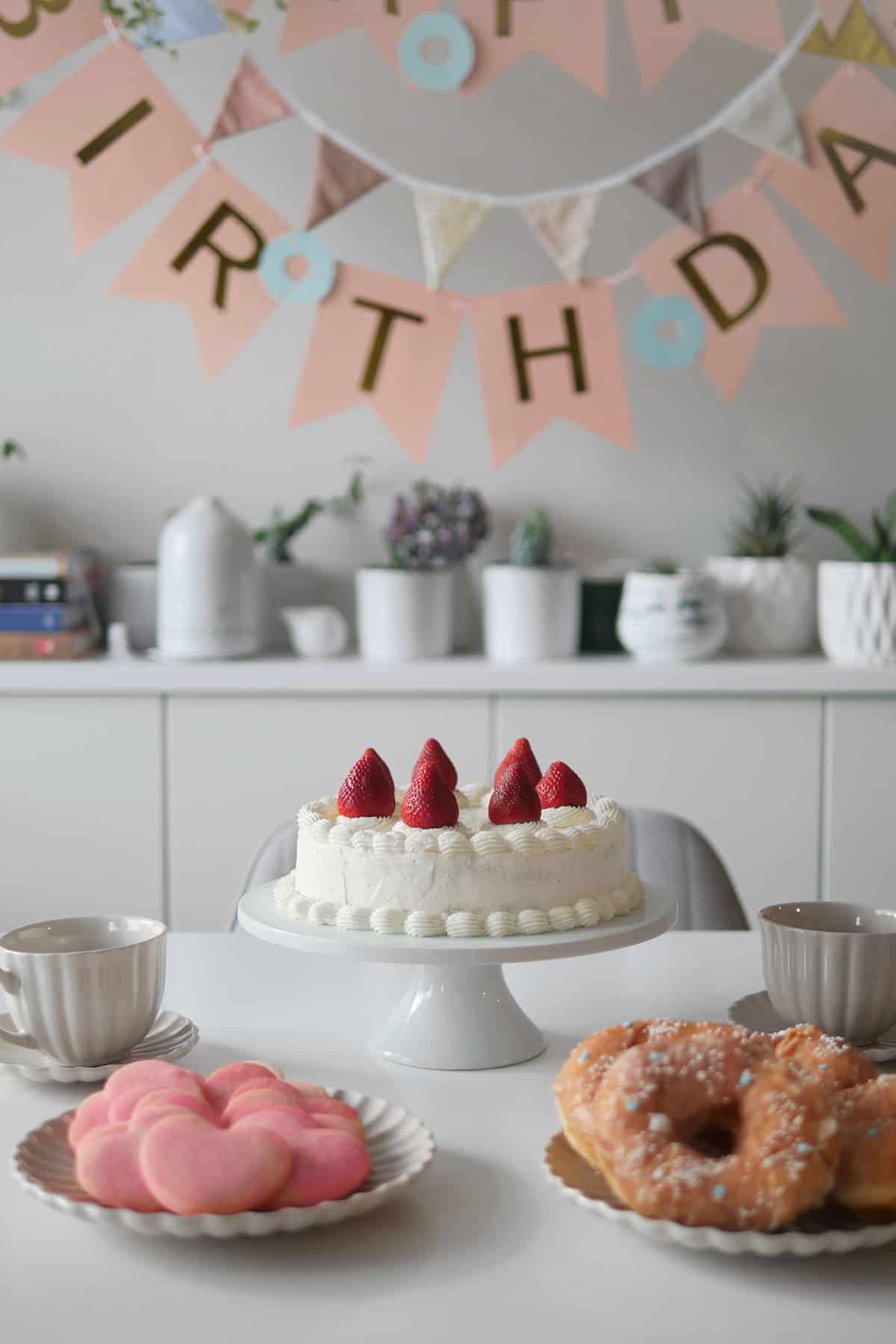 Chiffon cake that was baked in a round tube pan sits on top of a cake stand flanked by other baked goods. 