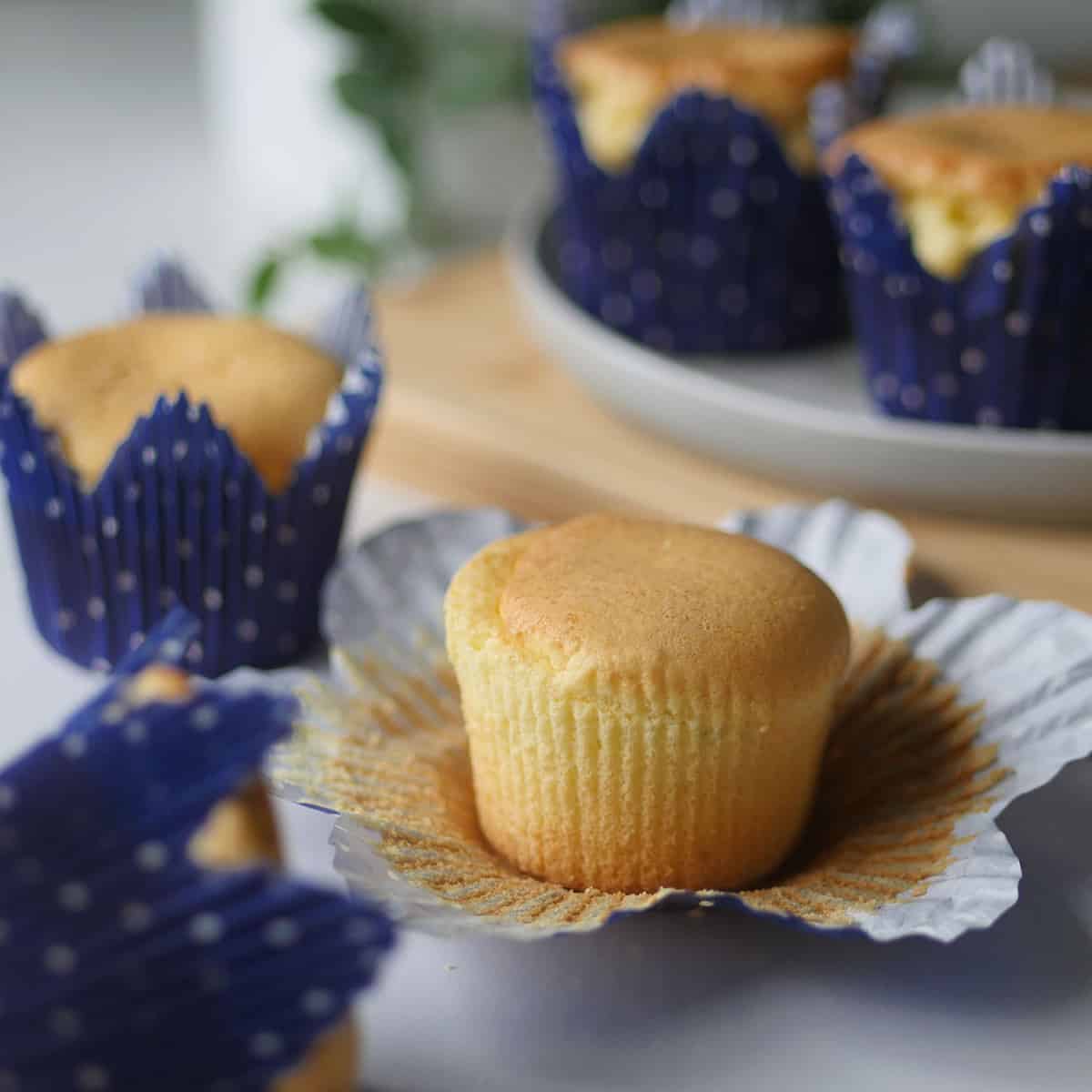 Chinese paper wrapped cupcakes with its wrapper opened exposing a bouncy golden cake.