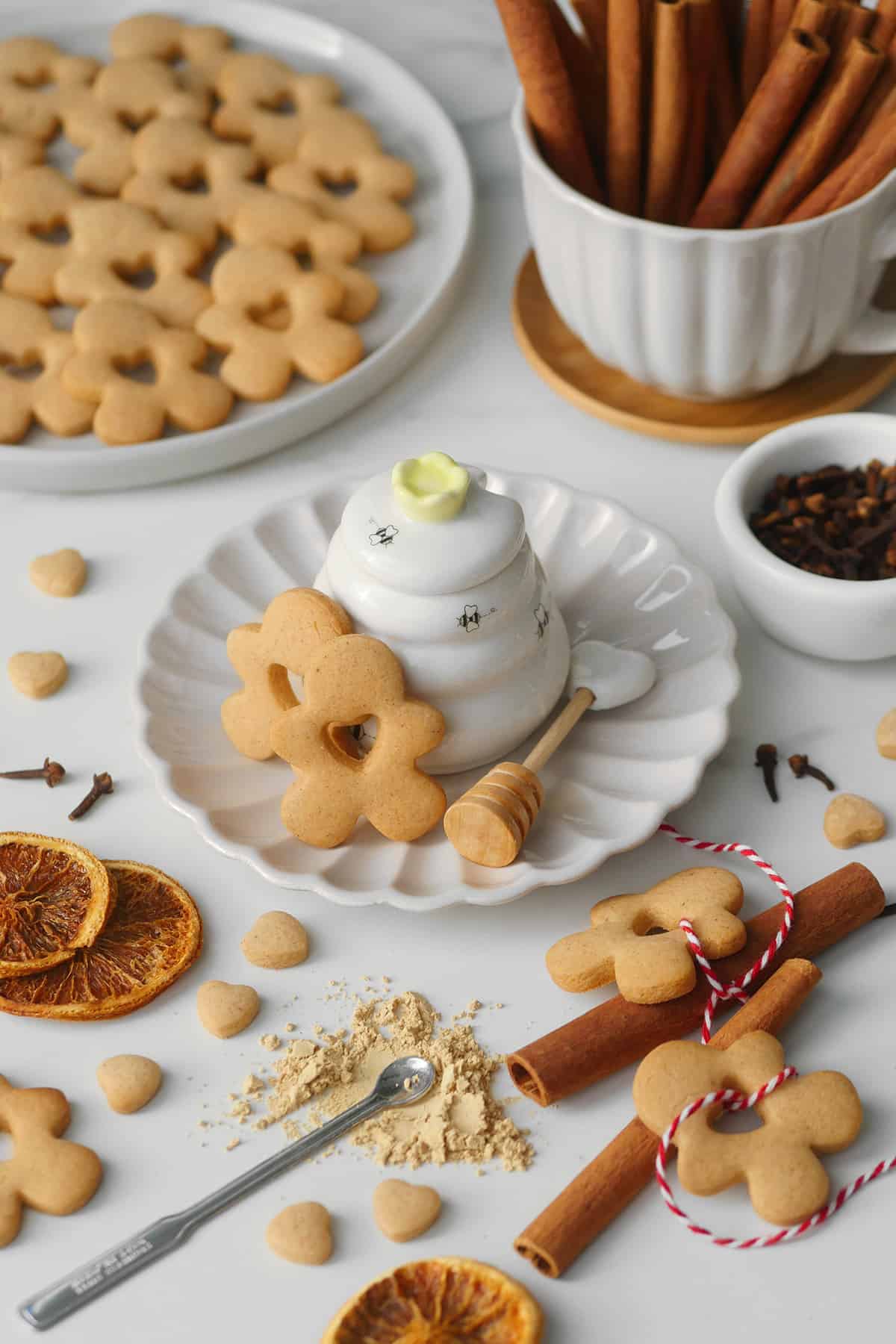 A small honey pot shaped like a bee hive is flanked by golden colored gingerbreadmen. 