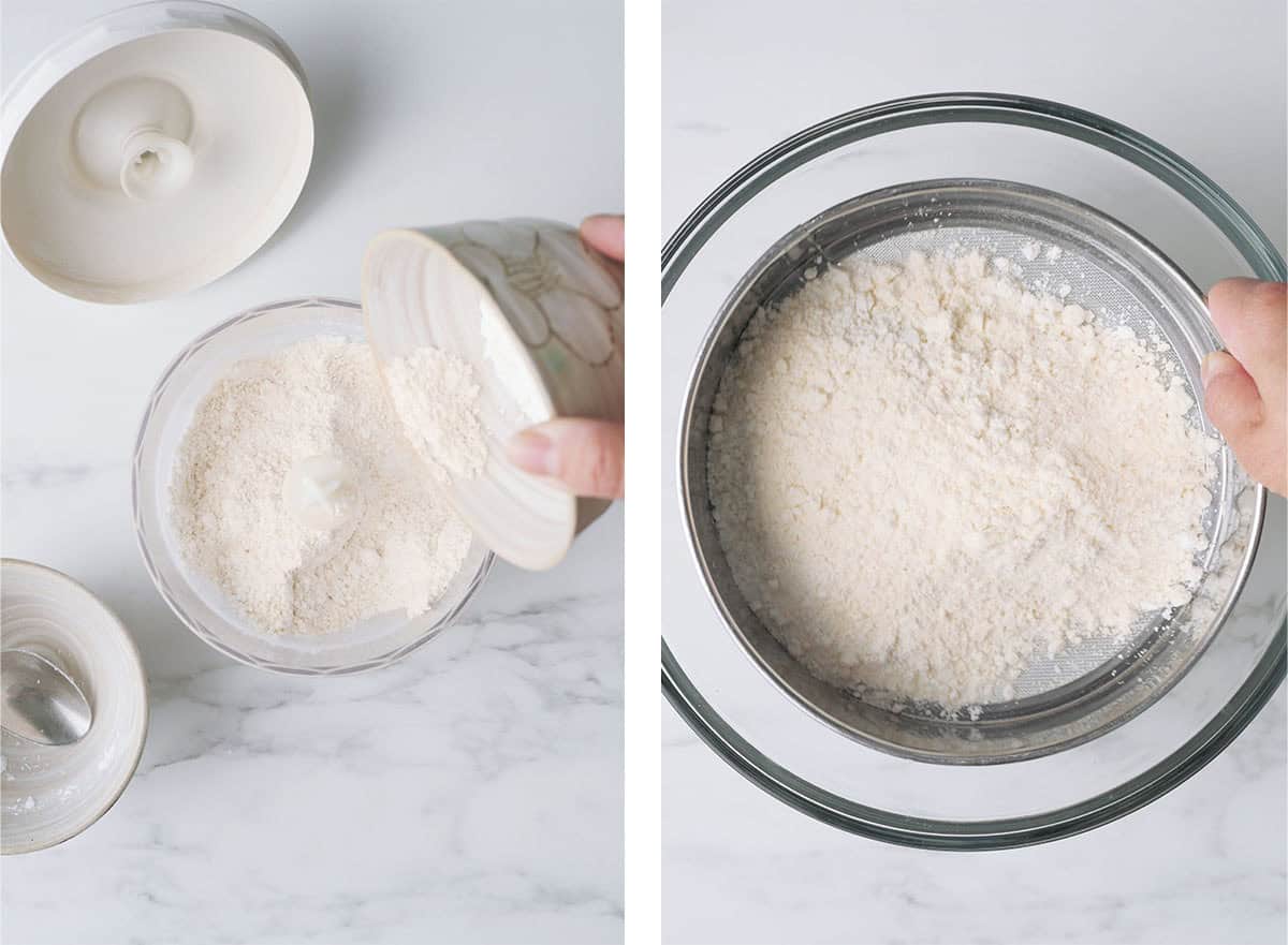 A hand is pouring almond powder and powdered sugar into a food processor and then sifted in a sieve. 