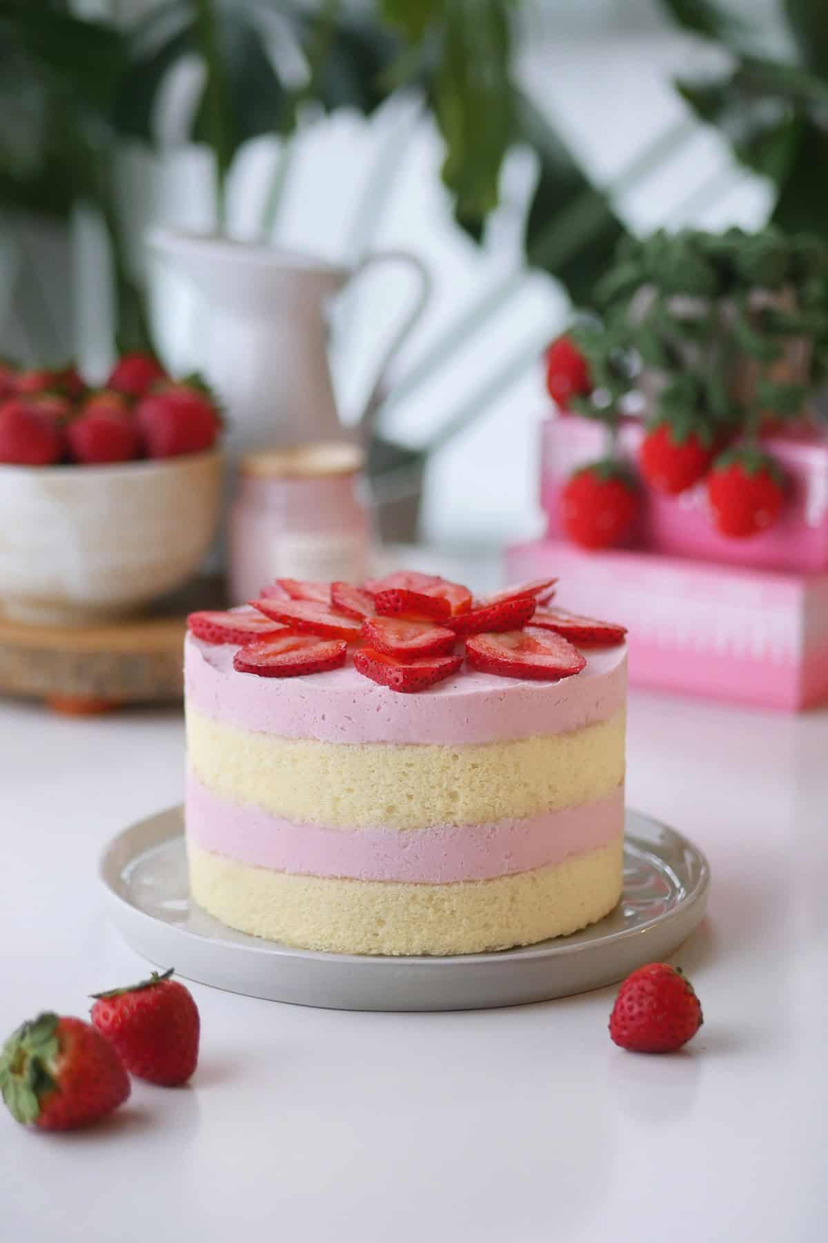 Side profile of a whole strawberry mousse cake showing alternating layers of cake and mousse. 