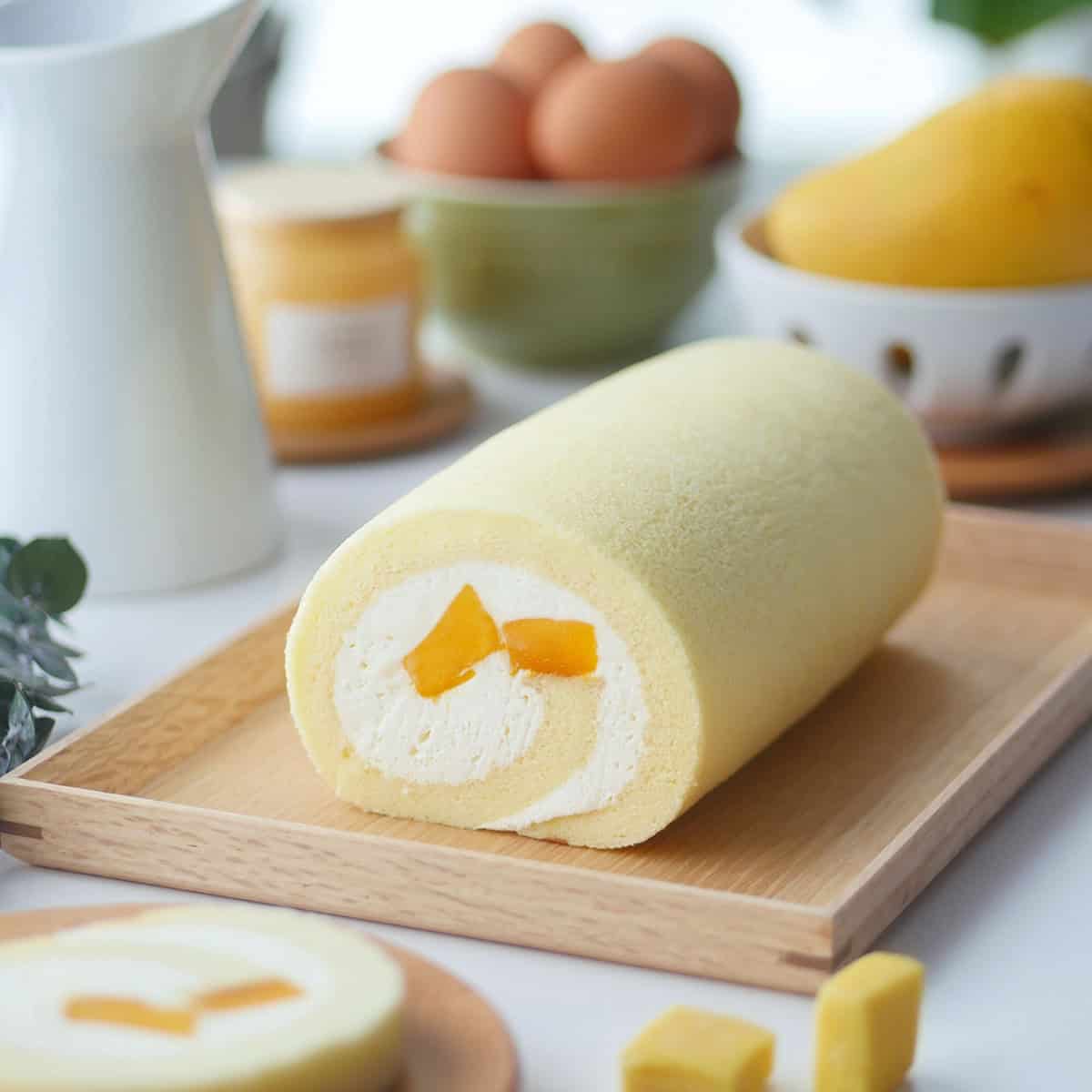 Side view of a mango cake roll revealing the fresh cream swirl and fresh mango chunks inside.