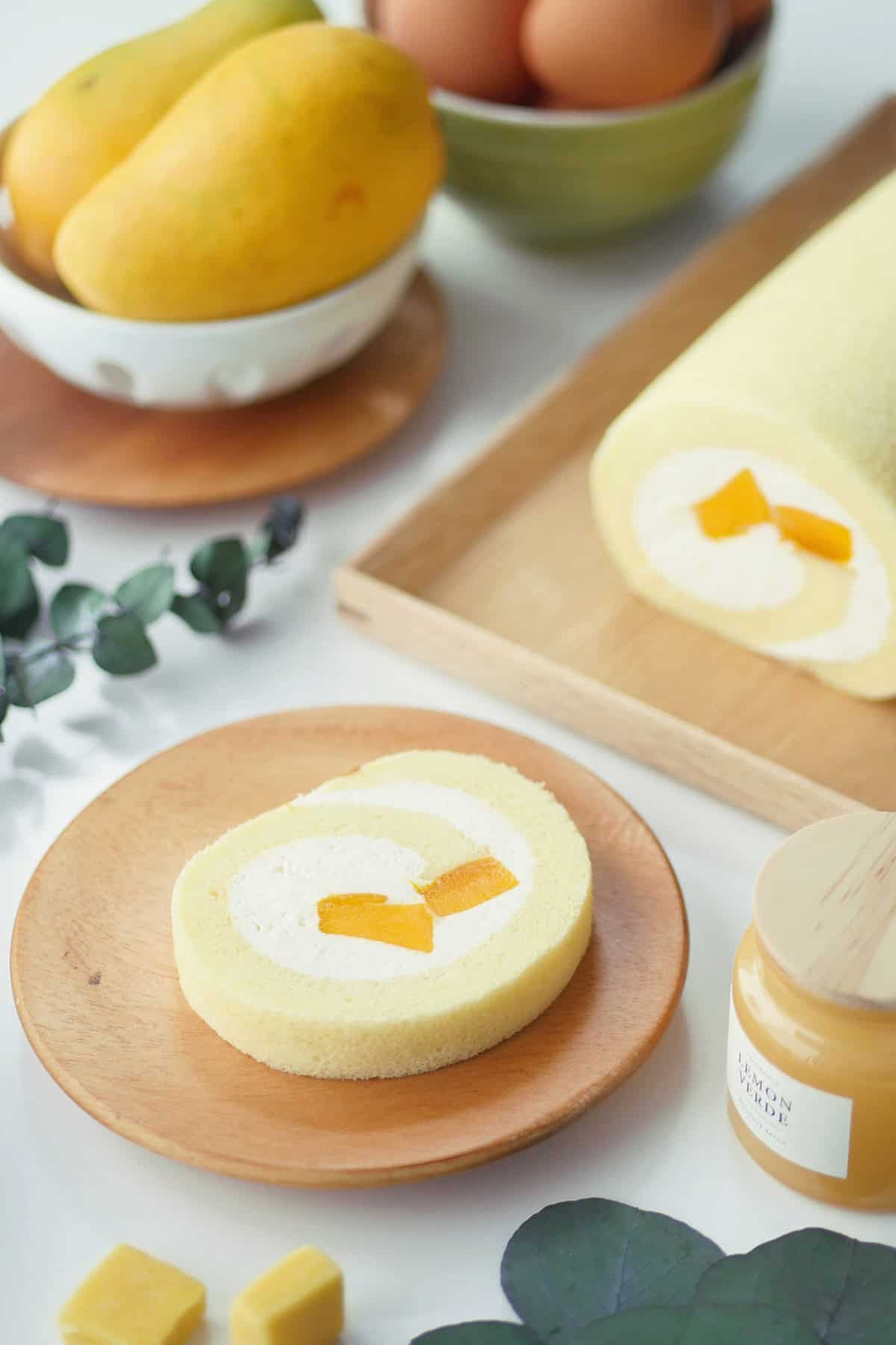Close up of a soft looking mango cake roll revealing 2 cubes of fresh juicy mango that is rolled inside. 