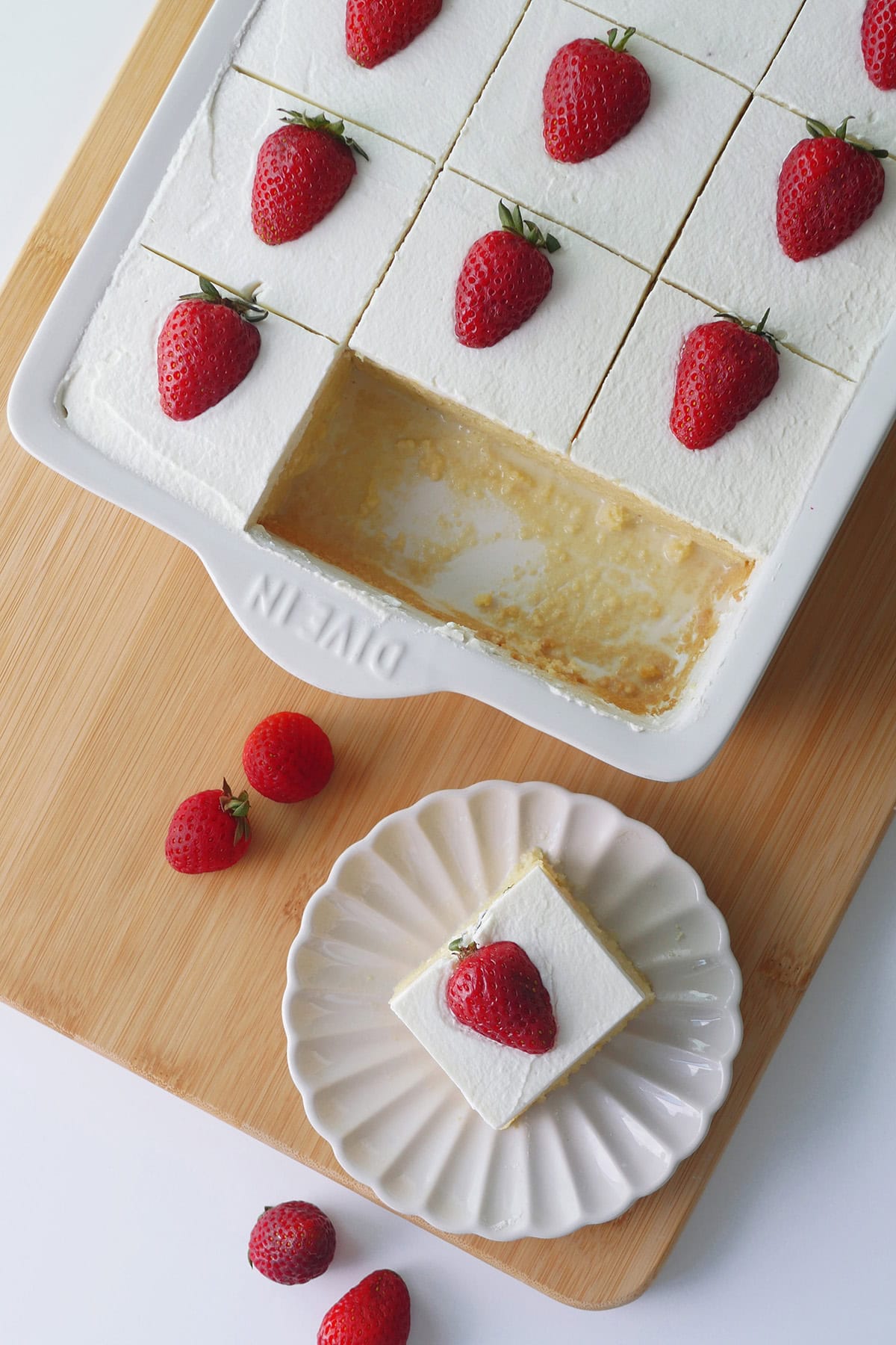 Top down close up view of a sheet pan with Tres Leches cake with two pieces cut out. Milk is pooling a little on the bottom of the pan. 