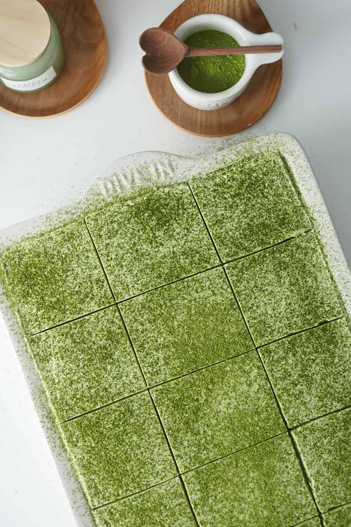 A top down view of a large rectangular ceramic baking pan filled with Tres Leches cake dusted with Matcha green tea powder.