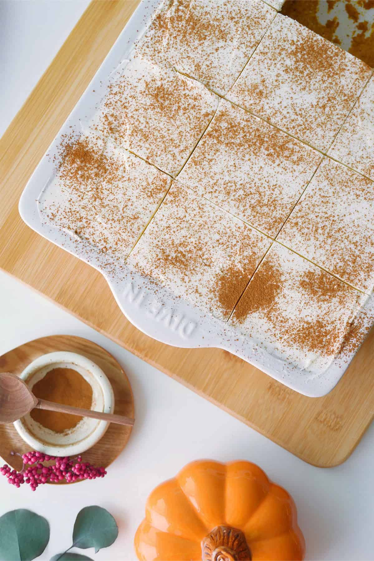 Top down view of pumpkin spice Tres Leches cake in a sheet cake pan cut into symmetrical sqaure slices. 