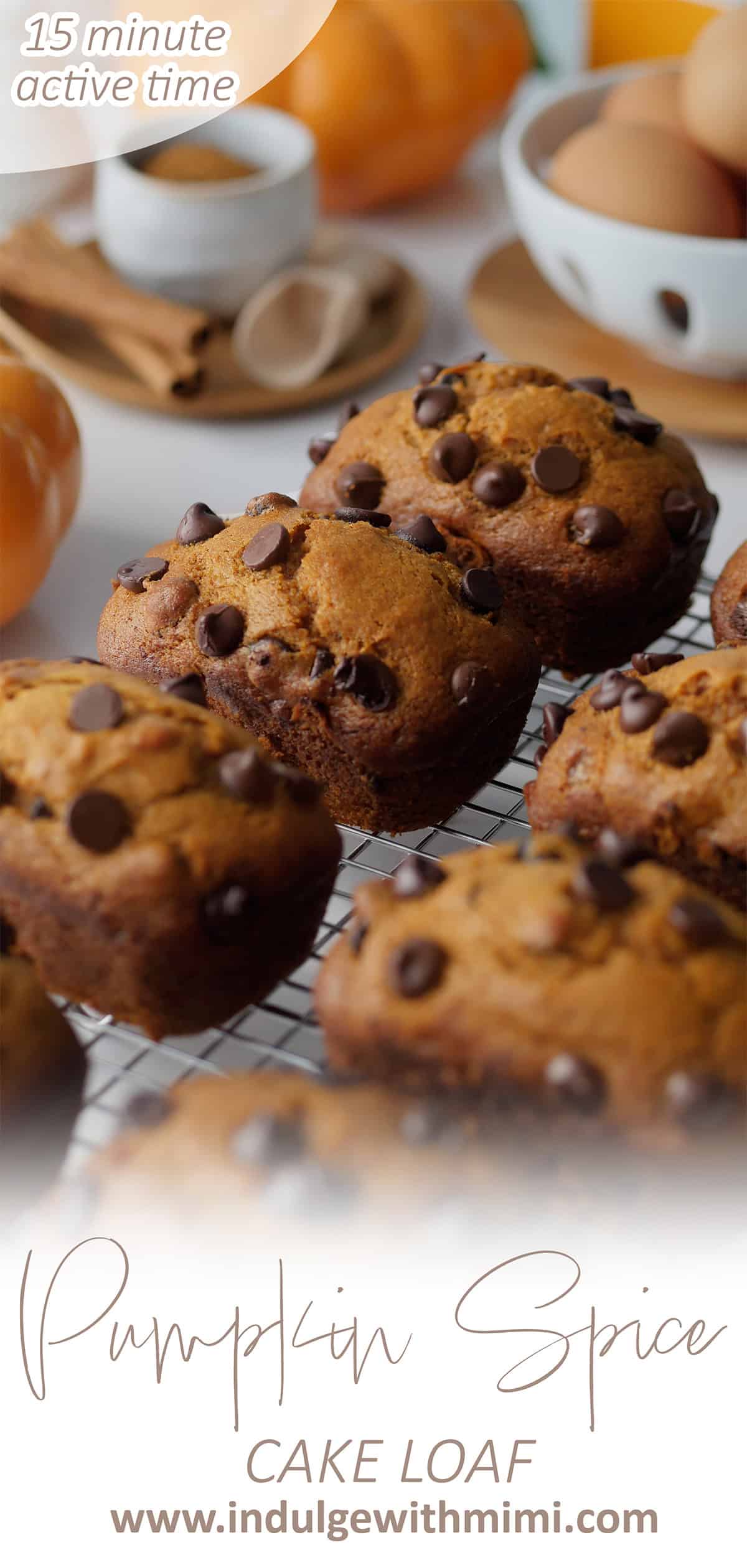 Close up of mini pumpkin cake loaves on a cooling rack, out of focus in the background are fall spices, cinnamon sticks and a little pumpkin.