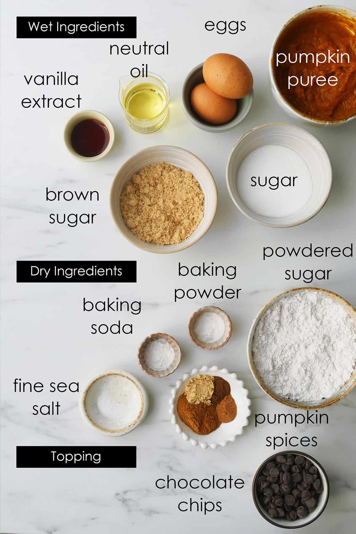 Ingredients for pumpkin cake loaves lad out on a marble counter. 