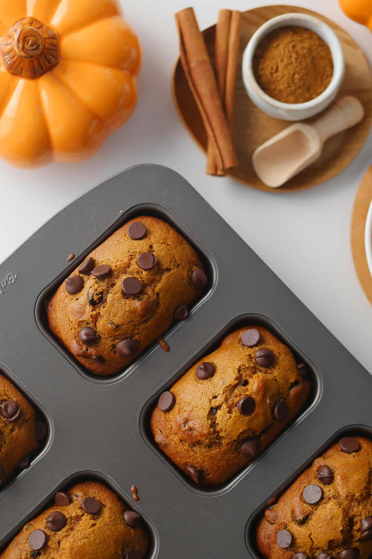 Top down view of mini pumpkin cake loaves topped with chocolate chips resting in a cake loaf pan. 