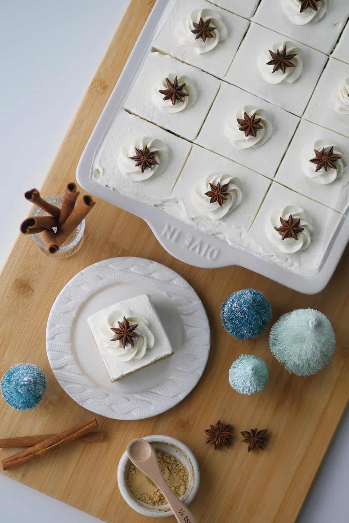 Gingerbread spice tres leches cake in a pan shown next to it with one slice cut out and placed on a small dessert plate.